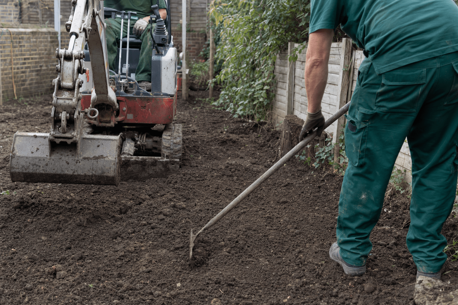 two-person team regrading a wet clay back garden with a small digger in Lewisham SE13